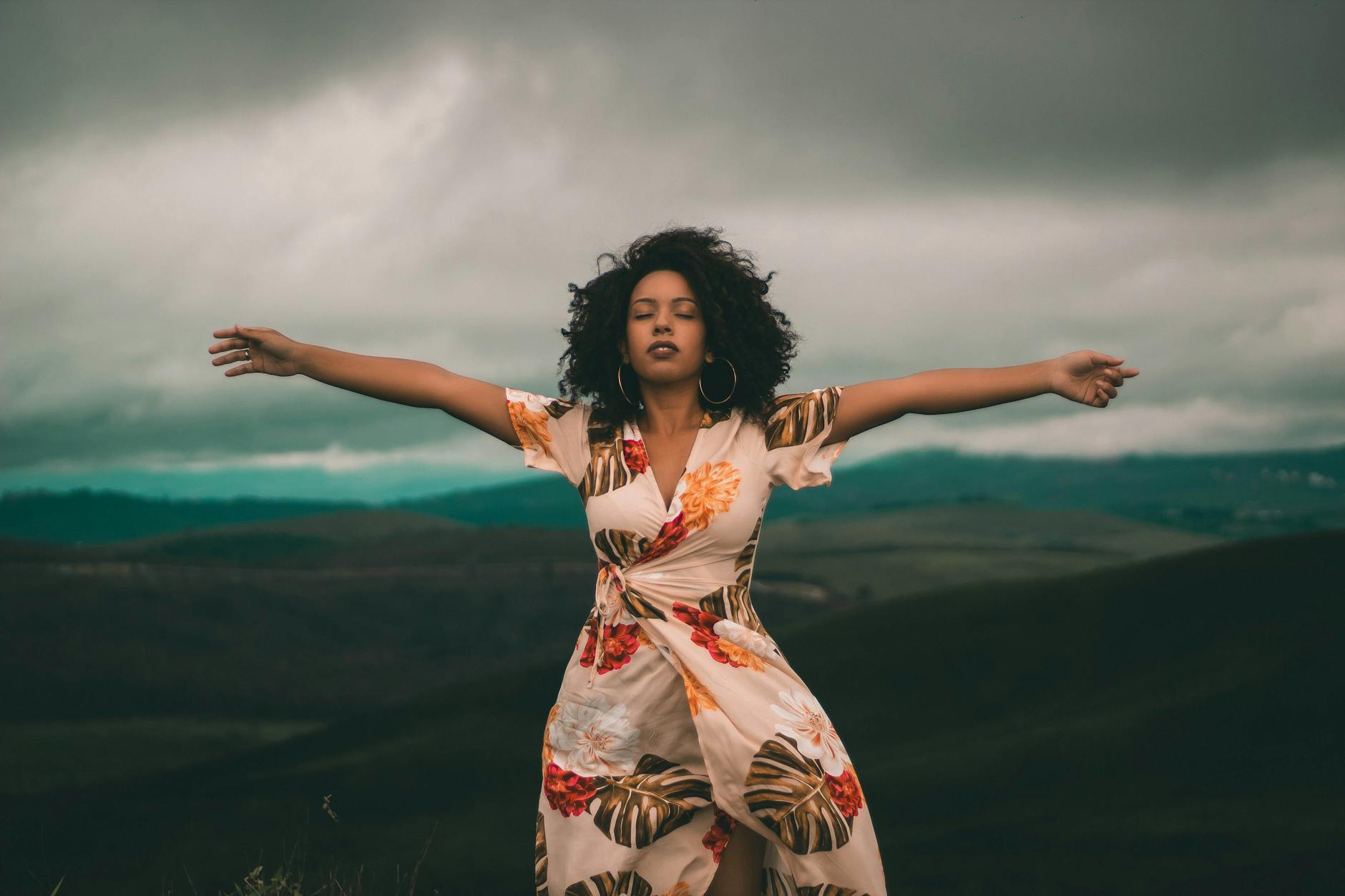 woman in white and red floral dress standing on green grass field