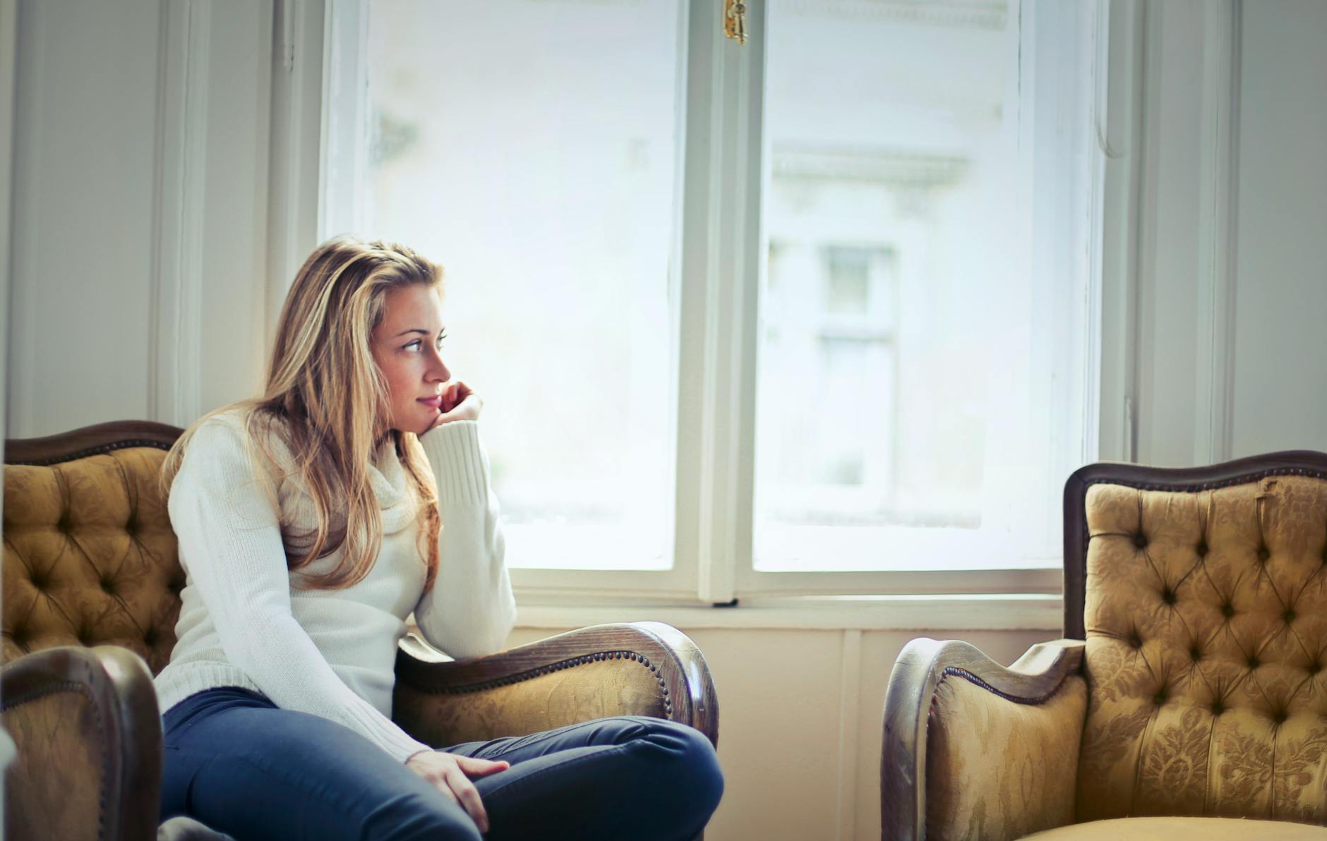 photography of woman sitting on chair near window